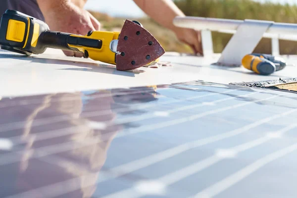 Male hands installing flexible solar panel on rv campervan or repair camper car roof.