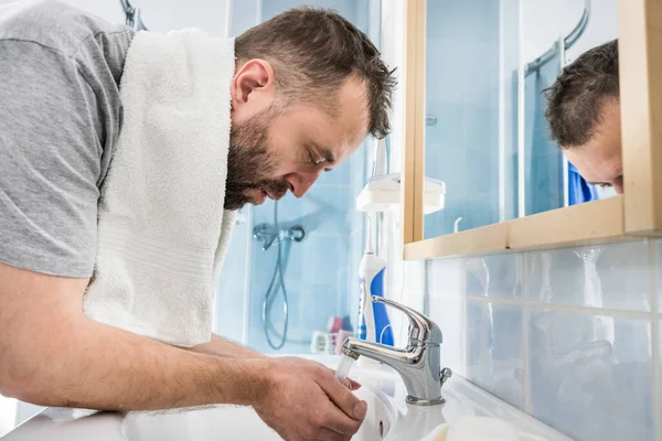男は自分の顔に水を撒き 自分自身を洗い 個人的な衛生管理をする 朝の気分がいい — ストック写真