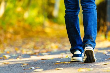 Person wearing casual sneakers shoes and blue jeans trousers walking outdoor. Stylish urban fashion details. clipart