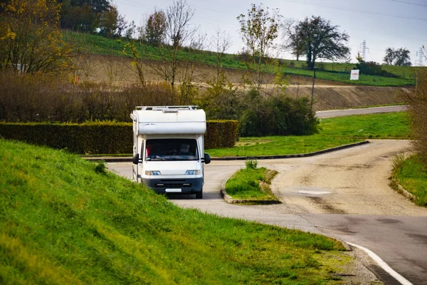 Camper car recreational vehicle with alcove parking on roadside. Holidays and travel in motor home.