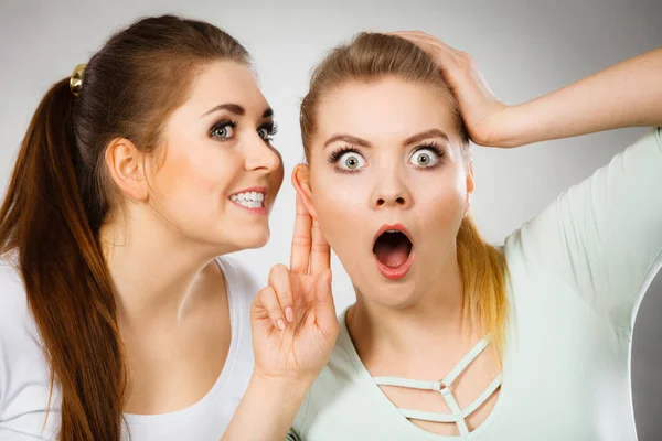 年轻女人告诉她的朋友一些秘密 两个女人在聊天 激动的女孩低声对着耳朵说话 — 图库照片