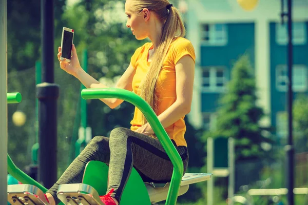 Молодая Женщина Тренируется Открытом Спортзале Девушка Держит Мобильный Телефон Делая — стоковое фото