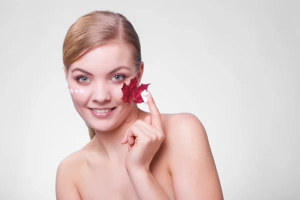 Soins de la peau. Visage de jeune femme fille avec feuille d'érable rouge. — Photo