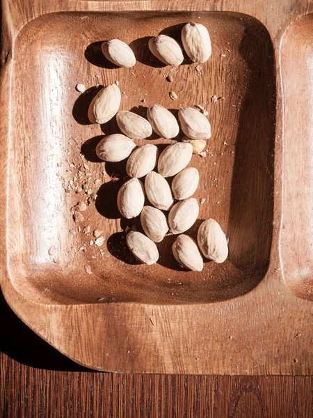 Orzeszki pistacjowe w drewnianej misce. Niezdrowa żywność. — Zdjęcie stockowe