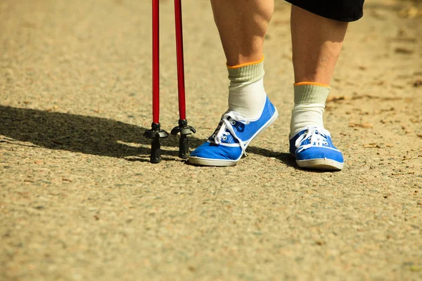 Mujer activa sénior nórdico caminando en el parque. piernas —  Fotos de Stock