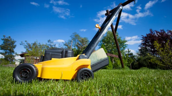 Trädgårdsarbete. Klippning gräsmatta med gul gräsklippare — Stockfoto