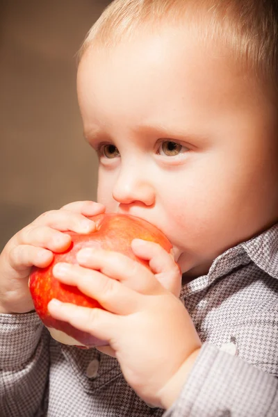 Kırmızı elma meyvesi yiyen tatlı erkek bebek. — Stok fotoğraf