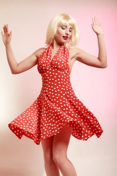 Piękna dziewczyna pinup w blond peruce i retro czerwona sukienka taniec. Strona. — Zdjęcie stockowe