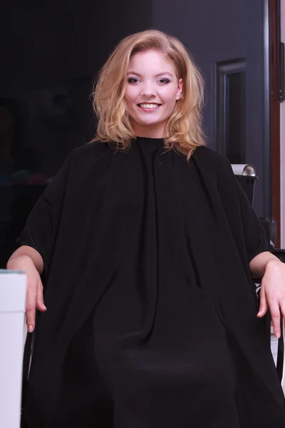 Улыбающаяся девушка с волнистыми светлыми волосами от парикмахера в салоне красоты — стоковое фото
