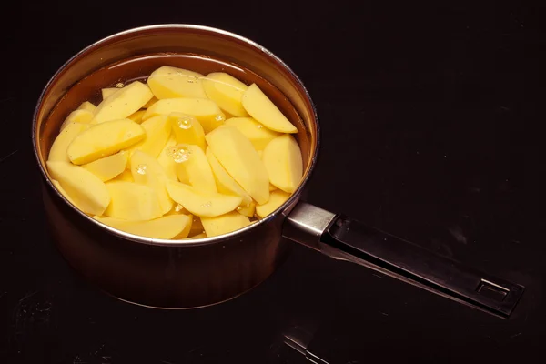 Raw peeled potatoes in pot pan on black. Healthy food. — Stock Photo, Image