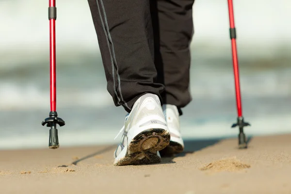 Caminhada nórdica. Pernas femininas caminhadas na praia. — Fotografia de Stock