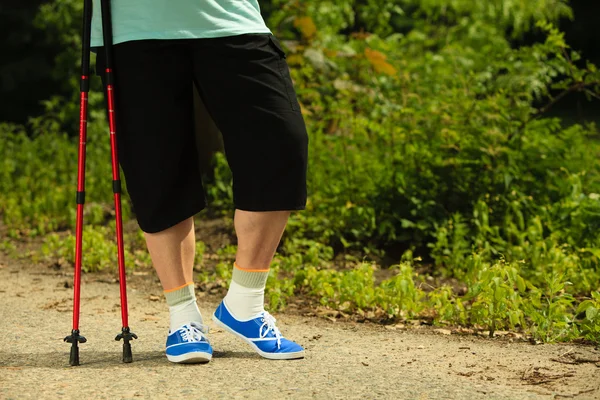 Active senior legs in sneakers nordic walking in a park. — Stock Photo, Image