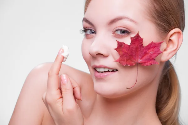 Huidverzorging. Gezicht van jonge vrouw meisje met rode esdoorn blad. — Stockfoto