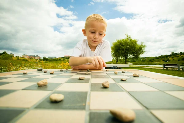 Niño jugando damas o damas juego de mesa al aire libre —  Fotos de Stock