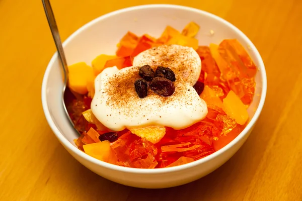 Fruit jelly in bowl with whipped cream and raisin — Stock Photo, Image