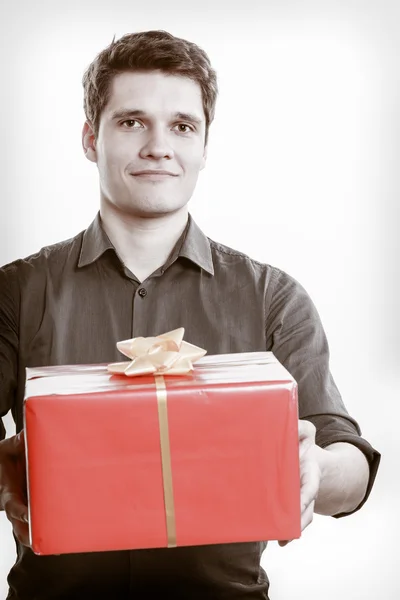 Holiday. Man giving red gift box with golden ribbon — Stock Photo, Image