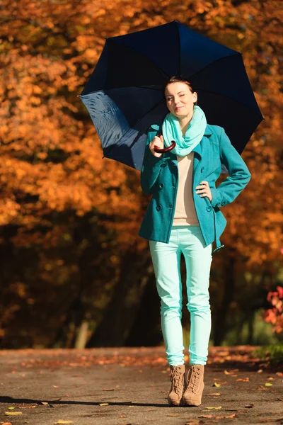 Mädchen spaziert mit blauem Regenschirm durch herbstlichen Park — Stockfoto