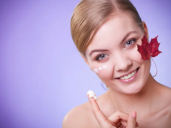 Huidverzorging. Gezicht van jonge vrouw meisje met rode esdoorn blad. — Stockfoto