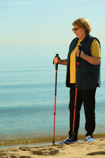 Aktywna kobieta senior nordic walking na plaży — Zdjęcie stockowe