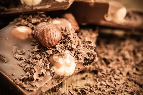 Chocolate shavings and pieces on wooden table — Stock Photo, Image