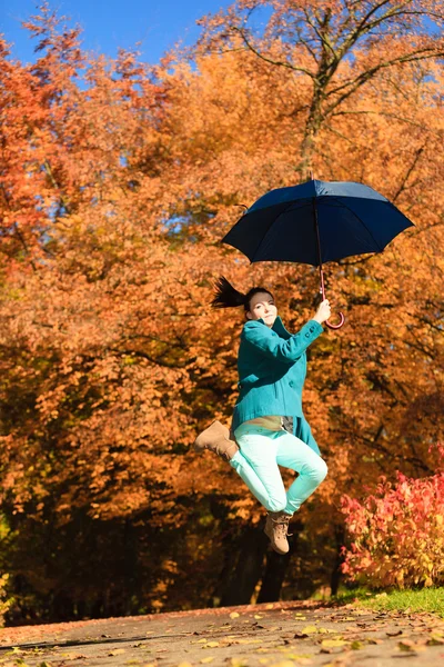 Menina pulando com guarda-chuva azul no parque outonal — Fotografia de Stock