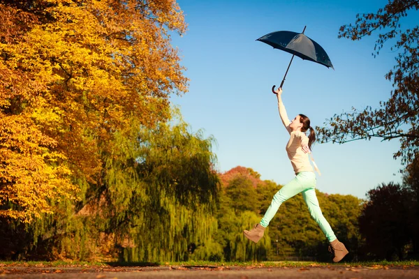 Mädchen springt mit blauem Regenschirm im herbstlichen Park — Stockfoto