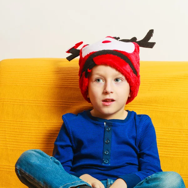 Niño en sombrero de reno de invierno rojo en casa —  Fotos de Stock