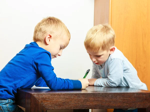 Pojkar barn med penna skriva gör läxor. Hemma. — Stockfoto