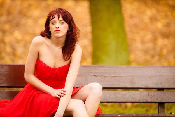 Kvinna i röd klänning på bänk — Stockfoto