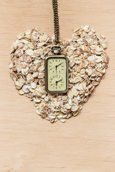 Σχήμα καρδιάς δημητριακά βρώμης και ρολόι — Φωτογραφία Αρχείου