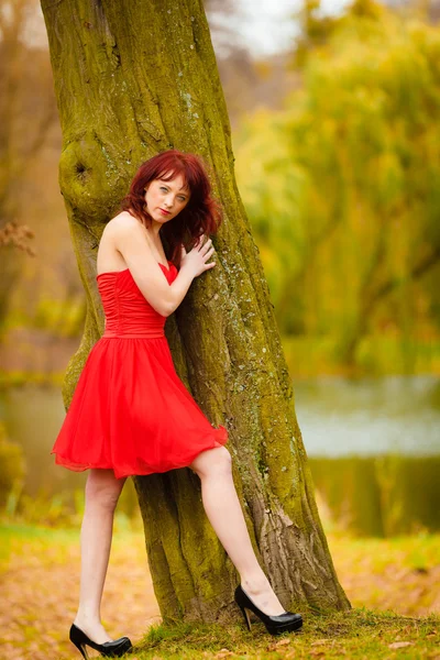 Vrouw in rode jurk in park — Stockfoto