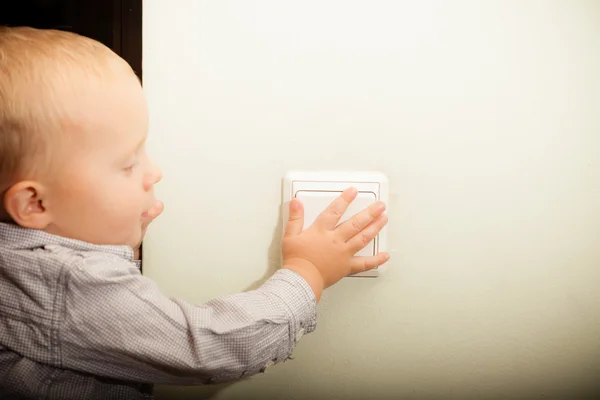 Baby boy turning on light — Stock Photo, Image