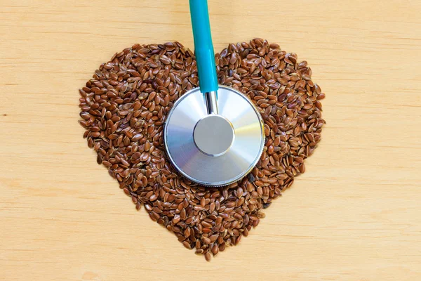 Nasiona lnu kształcie serca i stetoskop — Zdjęcie stockowe