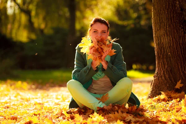 Mulher no parque segurando folhas de laranja — Fotografia de Stock