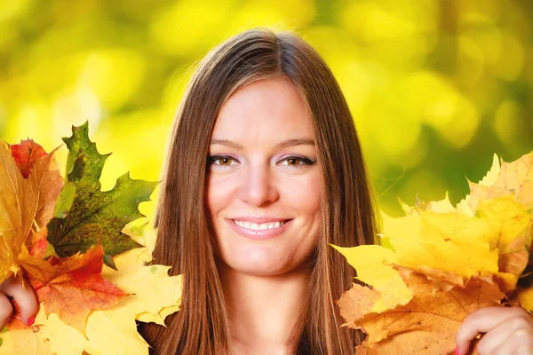 Woman holding autumnal leaves in park — Stock Photo, Image