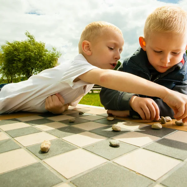 Children playing checkers board game — Stock Photo, Image