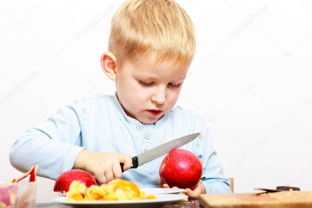 Boy cut apple with knife Stock Photo by ©Voyagerix 56015993