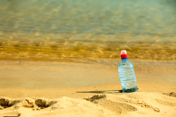 Botella de agua en la playa de arena — Foto de Stock
