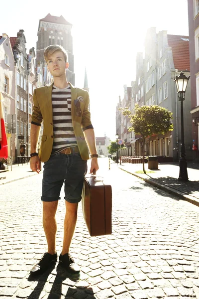 Young handsome man with suitcase on street — Stock Photo, Image