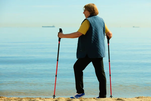 Active woman senior nordic walking on a beach — Stock Photo, Image