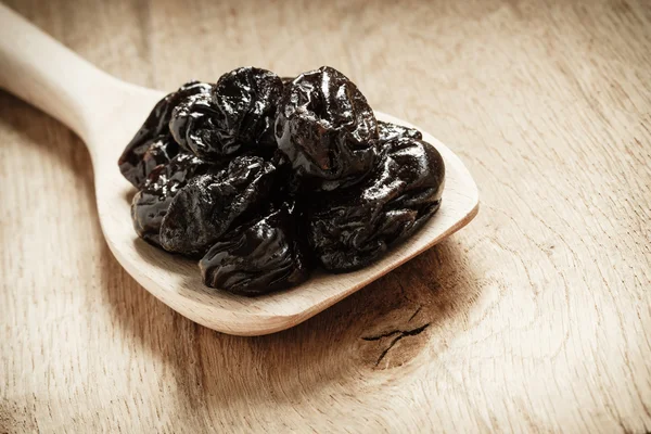 Dried plums on wooden spoon — Stock Photo, Image