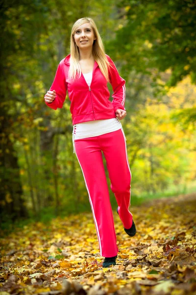Kobieta biegająca w jesiennym lesie. — Zdjęcie stockowe