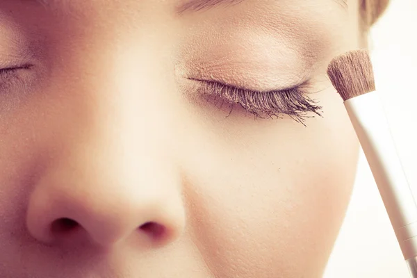 Vrouw aanbrengen van make-up met borstel — Stockfoto