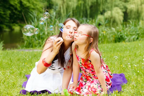 Madre y niña soplando burbujas de jabón —  Fotos de Stock