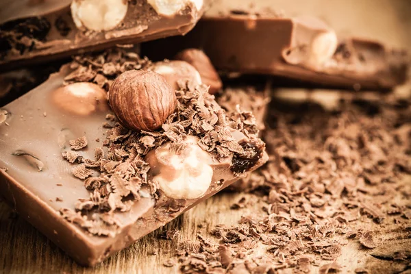 Chocoladeschilfers en stukken op houten tafel — Stockfoto