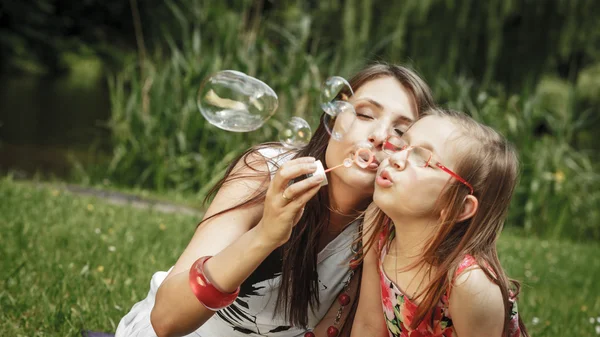 Moeder en meisje zeepbellen blazen — Stockfoto