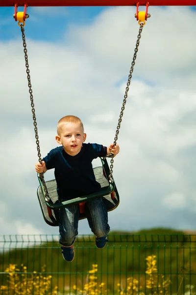 Ребенок веселится на качелях на открытом воздухе — стоковое фото