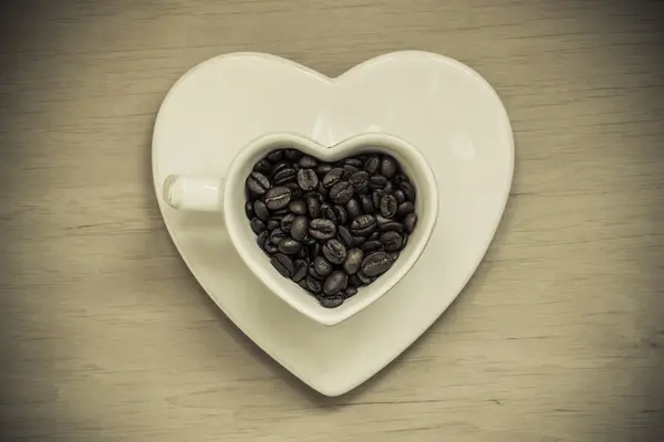 Copa en forma de corazón con granos de café en la mesa de madera —  Fotos de Stock