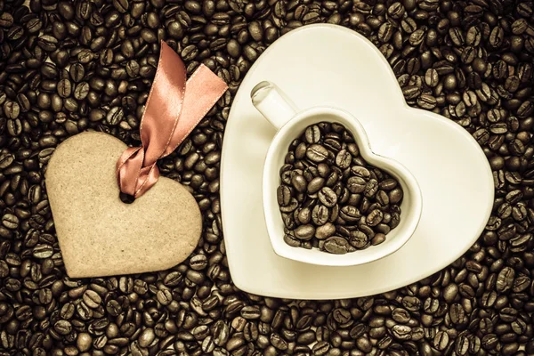 Coração em forma de copo e biscoito no fundo grãos de café — Fotografia de Stock