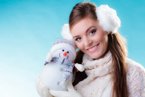 Žena v teplé oblečení drží hračka sněhulák. — Stock fotografie